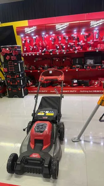 Akumulatorska rotacijska kosilnica Milwaukee. V ozadju vrhunsko orodje Milwaukee.